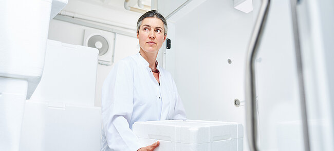 A woman carrying a white insulated box